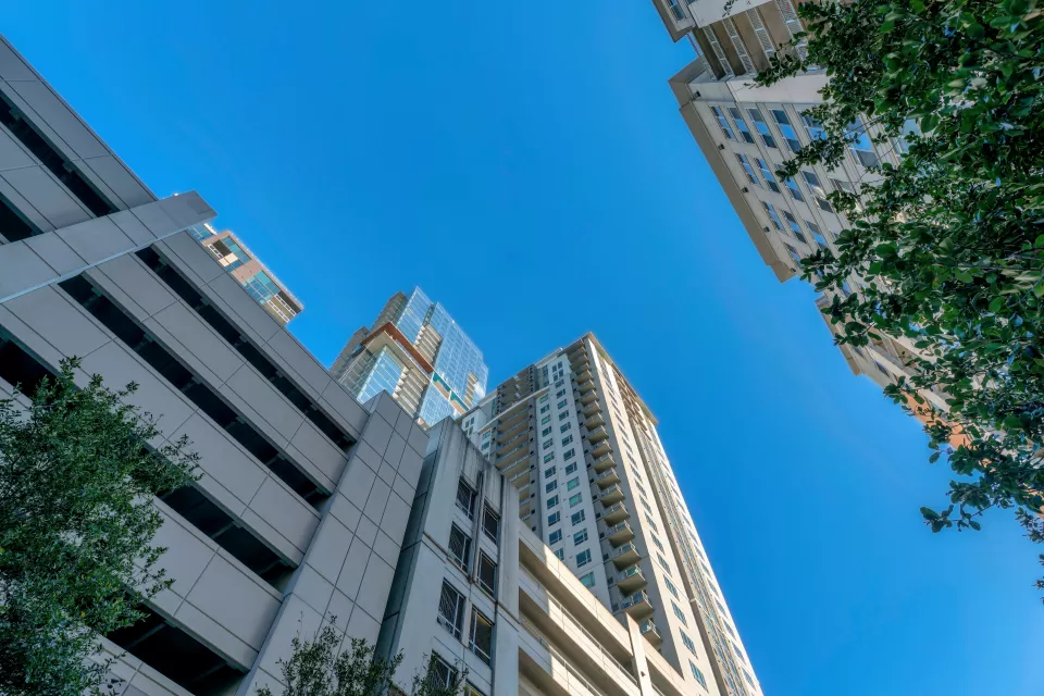 View from street level looking up at high-rise apartment building with multi0floor garage at bottom in Austin, Texas against blue sky
